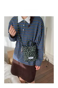 Detail view of small green leopard print crossbody bag worn with a striped polo shirt