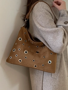 Brown suede tote bag with silver eyelets and leather strap shown on a fashion model