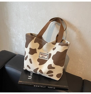 Detail of corduroy cow print tote bag with soft fabric texture and stitched brand label