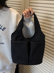 Borsa tote nera minimalista in tela con ampie tasche frontali per uso quotidiano