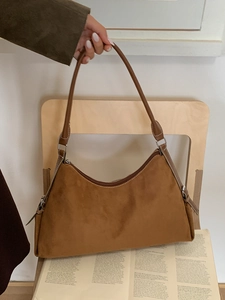 Sac à bandoulière hobo en daim marron au design rétro minimaliste sur une chaise