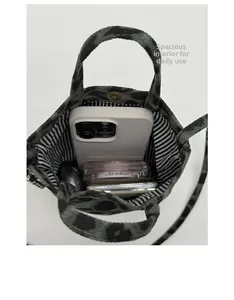 Internal view of green leopard print mini tote bag showing smartphone and makeup storage
