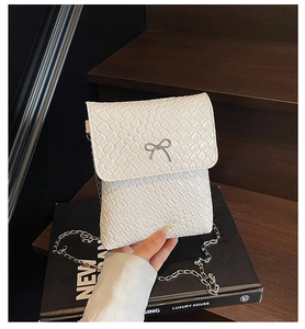 Detail of white woven texture shoulder bag with a silver metal bow buckle and chain