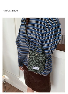 Detail of leopard print mini crossbody bag with logo patch and heart charm on model