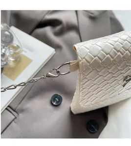 Detailed close-up of the silver metal lobster clasp and woven texture on a white bag