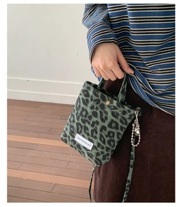 Detail of leopard print canvas bag with vintage green pattern and silver ball charm
