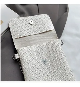 Close-up of white woven faux leather mini bag featuring silver magnetic buckle and chain strap