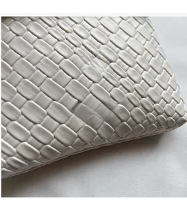 Close-up of beige woven texture featuring the embossed Nan Xiao Jie brand logo detail