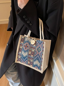Bohemian geometric woven handbag with white rope handles and wooden button closure