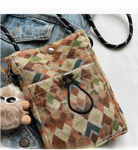 Close-up of bohemian woven phone bag with geometric patterns and plush doll charm