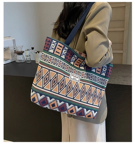 Detail of colorful woven canvas bucket bag featuring ethnic patterns and wide strap