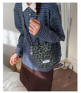 Detail of trendy leopard print crossbody bag showing mini size and green fabric texture