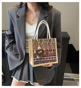Detail of ethnic embroidered tote bag with woven handles and plush monster charm pendant