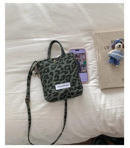 Detail of green leopard canvas mini bag with logo patch and heart keychain