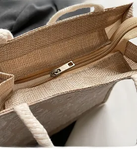 Detail of a linen tote bag showing smooth metal zipper and white woven handles