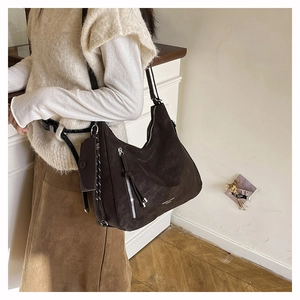 Detail einer braunen Wildleder-Hobo-Tasche mit silbernem Reißverschluss und Mini-Beutel