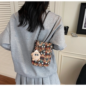 Détail d'un sac à bandoulière tissé bohème avec un adorable porte-clés monstre