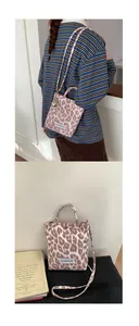 Close-up of pink leopard print canvas crossbody bag with metal snap and logo label