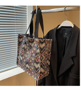 Detail of colorful geometric woven tote bag featuring soft ethnic texture and black handles