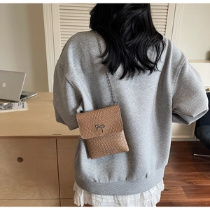 Close-up of woven leather texture and silver bow detail on the stylish brown crossbody bag