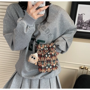 Détail d'un sac de téléphone tissé géométrique coloré avec un ours en peluche