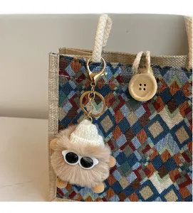 Close-up of a brown plush monster bag charm with knit hat and sunglasses details