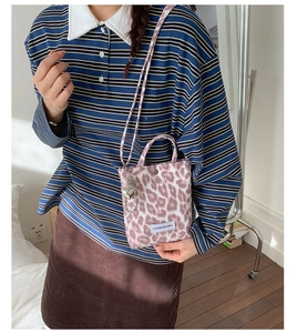 Detail view of pink leopard print crossbody bag with a silver heart-shaped pendant charm