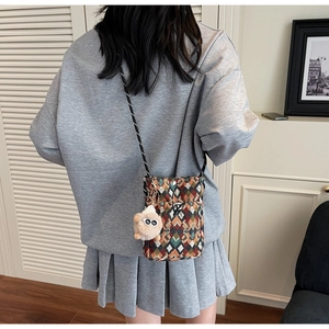 Détail d'un sac bandoulière bohème en toile avec motifs géométriques et pendentif