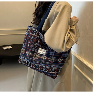 Detail view of woven geometric patterns and logo patch on the blue canvas bucket tote