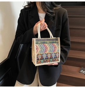 Close-up of bohemian woven handbag featuring colorful ethnic embroidery and rope handles