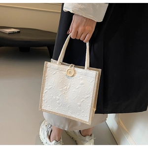 Detail of linen handbag with 3D embossed rose texture and decorative wooden button