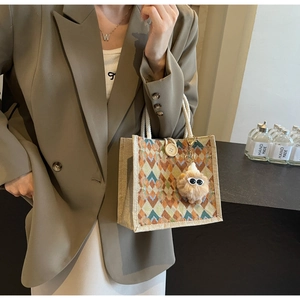Detail of rhombic pattern linen tote bag with cotton rope handles and plush monster charm