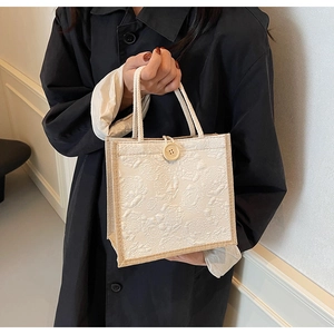 Detail view of a white jacquard handbag featuring embossed rose texture and a wooden button