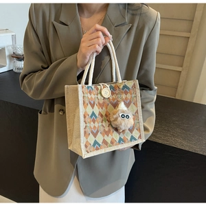 Detail of linen tote bag with geometric patterns, wood buckle, and plush charm