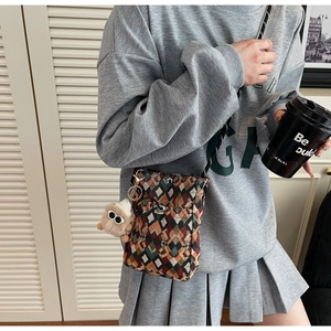 Detail of bohemian jacquard crossbody bag with geometric diamond pattern and plush charm
