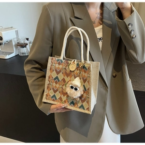 Detail of geometric woven handbag with rope handle, wood button, and plush bear charm