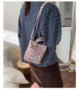 Fashionable leopard print crossbody bag worn by a model in a cozy bedroom setting