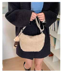 Détail d'un sac bandoulière beige en polaire avec breloque d'ours et bandoulière large