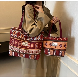 Detail of vintage ethnic canvas bucket bag set with red handles and geometric patterns