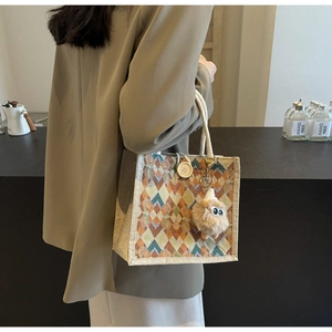 Detail of geometric knit tote with orange-green patterns, rope handle and sheep charm