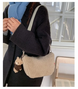 Détail du sac demi-lune en polaire beige avec bandoulière blanche et pendentif ours