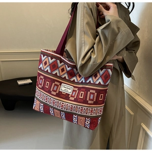 Detail view of burgundy canvas bucket bag with bohemian geometric patterns and shoulder strap