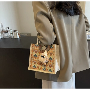 Detail of linen tote bag featuring geometric rhombus patterns and soft plush charm