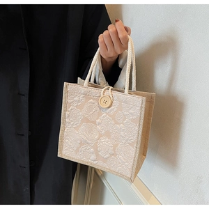 Detail of rose floral jacquard tote bag featuring linen handle and wooden button closure