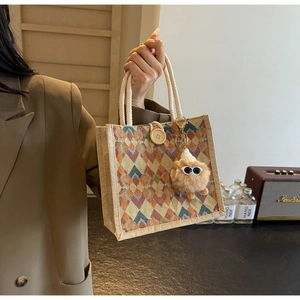 Macro detail of geometric woven handbag with rope handles and plush monster charm