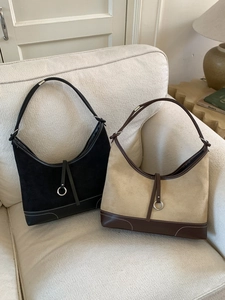 Retro suede hobo tote bag in black and beige contrast stitching on a minimalist sofa