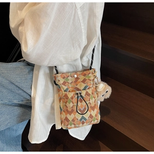 Détail du sac à téléphone tissé bohème avec motifs géométriques et pendentif en peluche