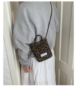 Close-up of leopard print canvas bag detailing with brand label and crossbody strap