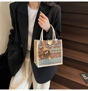 Detail of woven tote bag with jacquard pattern, large button, and plush monster charm