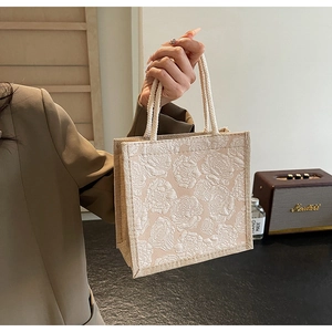 Close-up of beige linen tote bag featuring 3D floral jacquard and woven rope handles